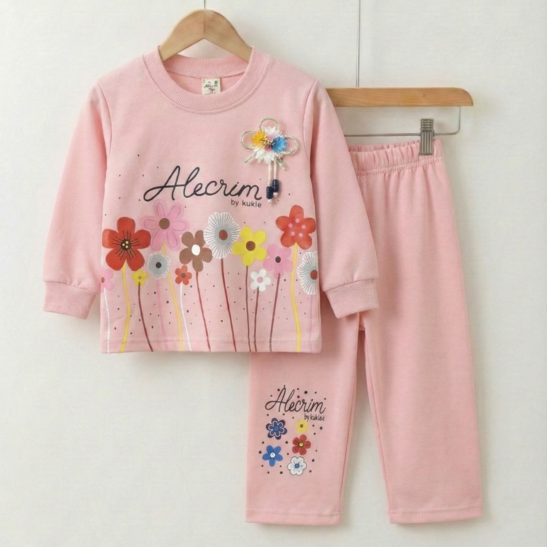 Pink children's pajama set with floral designs on a white background